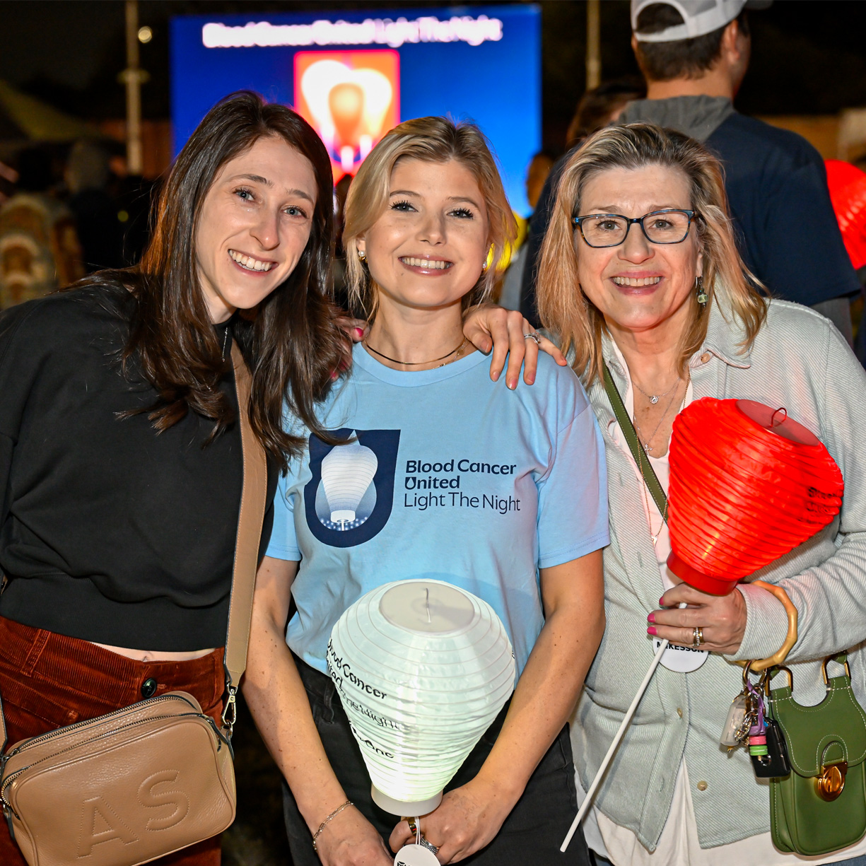 survivor participant at a Light The Night event standing holding white lantern and her family 